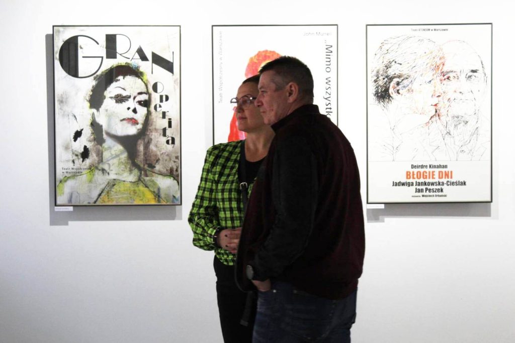 Kobieta z mężczyzną zwiedzający wystawę na tle plakatów