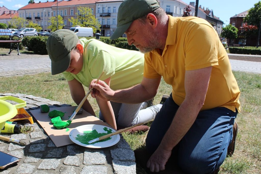 Tata z chłopcem malują kamień na zielono