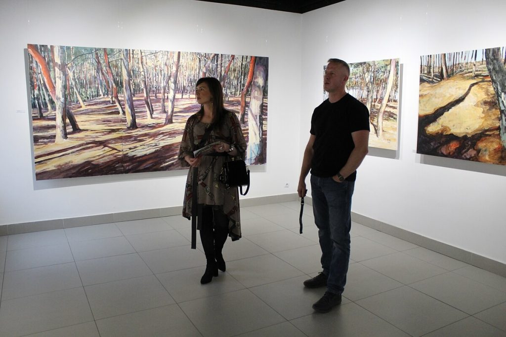 Kobieta z mężczyzną zwiedzają wystawę obrazów Aleksandry Rey