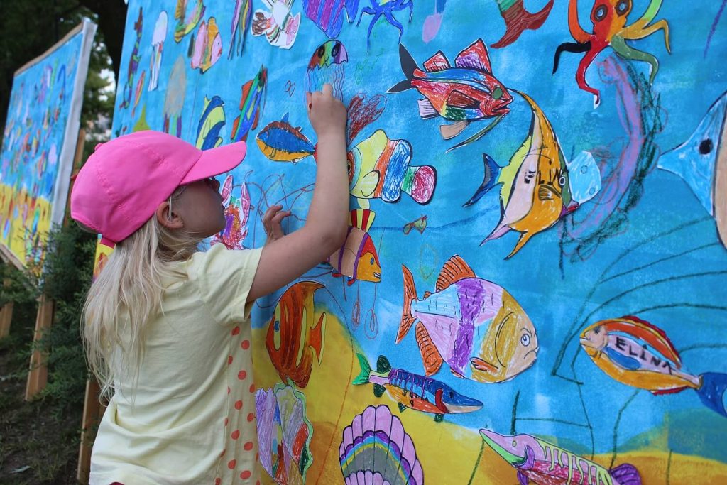 Dziewczynka maluje na tablicy z podwodnym światem