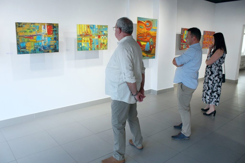Dwaj mężczyźni i kobieta zwiedzający wystawę Anny Wąsikiewicz
