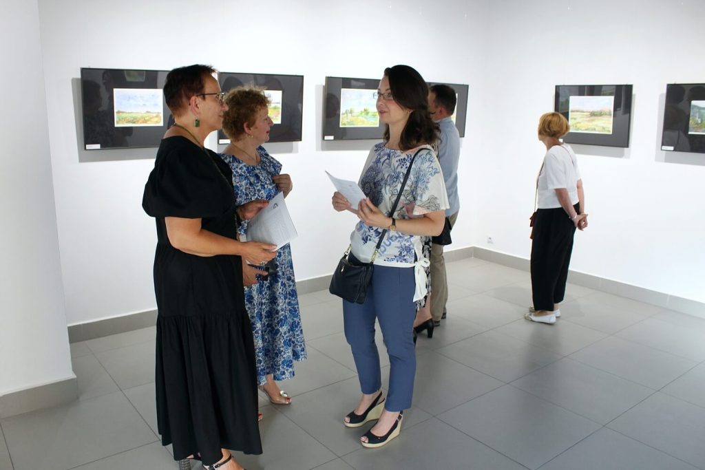 Uczestnicy wystawy rozmawiający o obrazach Anny Wąsikiewicz