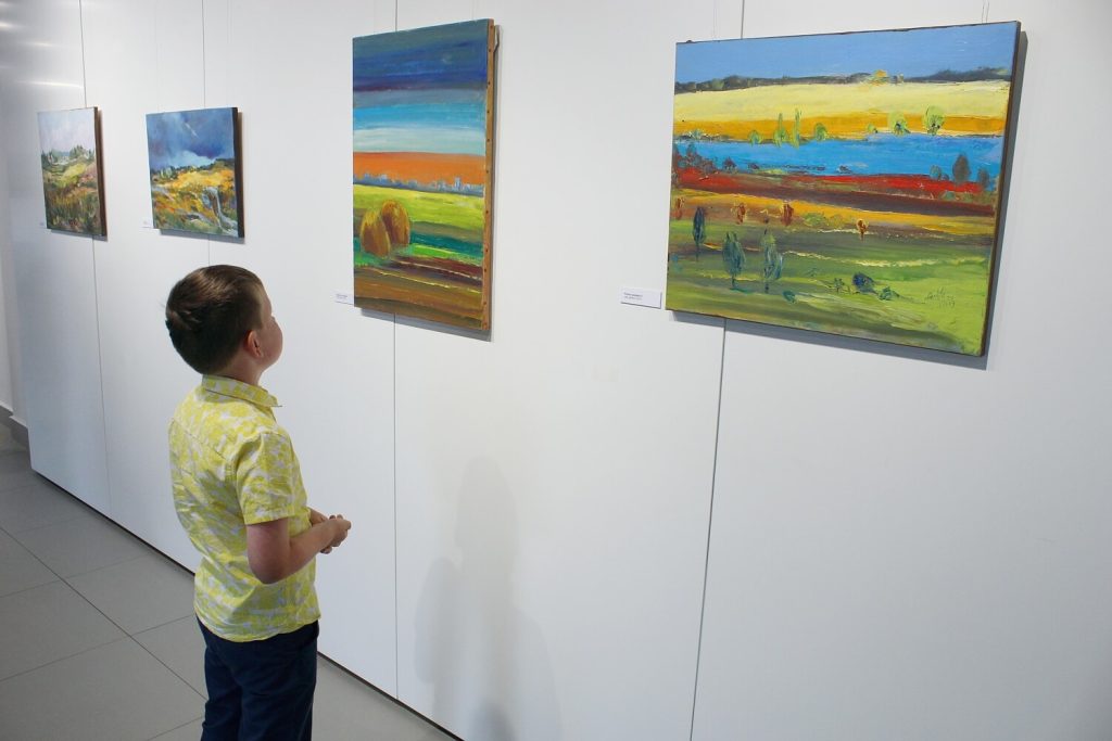 Chłopiec oglądający obrazy Anny Wąsikiewicz
