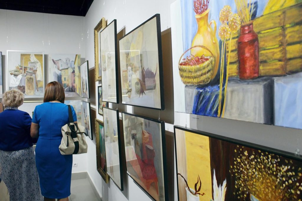 Obrazy i zwiedzający w trakcie wystawy Malarstwo i rysunek z pracowni plastycznej