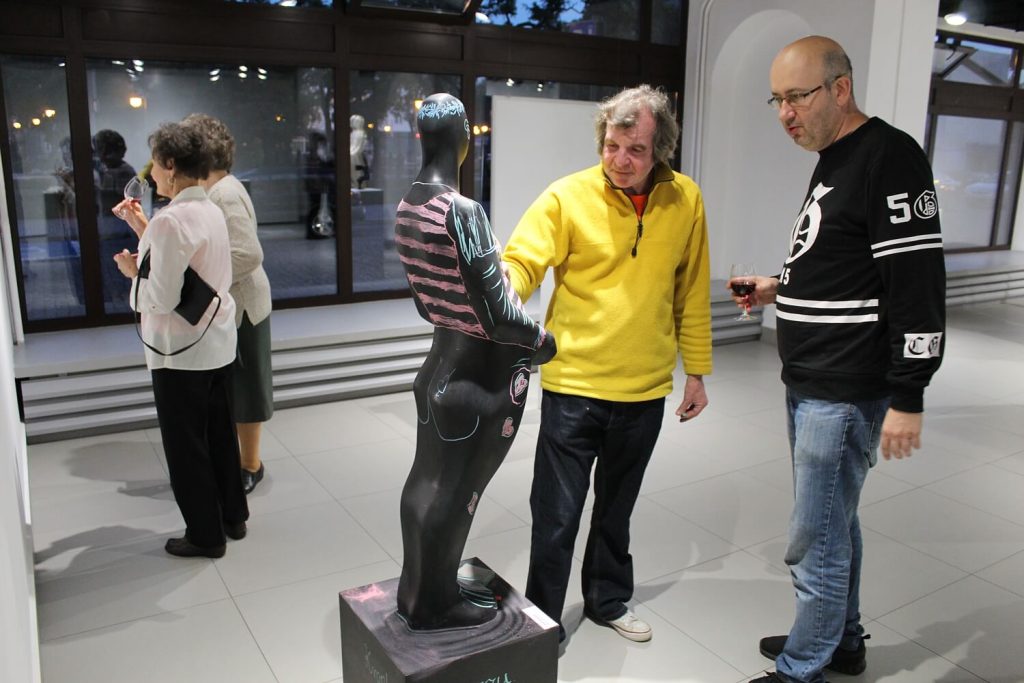 Zwiedzający wystawę mężczyźni oglądają rzeźbę Emilii Boguckiej