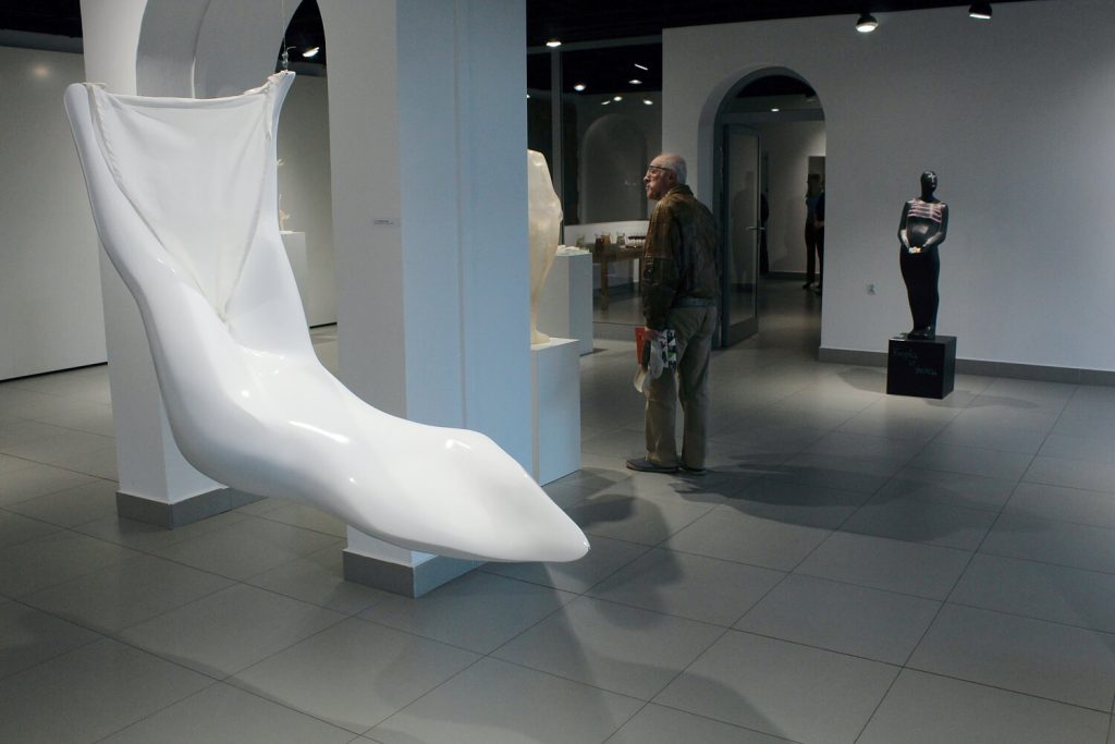 Rzeźba Emilii Boguckiej na pierwszym planie w tle zwiedzający wystawę mężczyzna