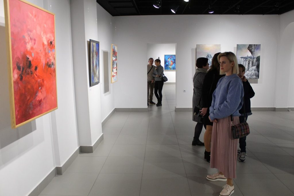 Kobieta przyglądająca się obrazowi podczas wystawy Trzy Światy