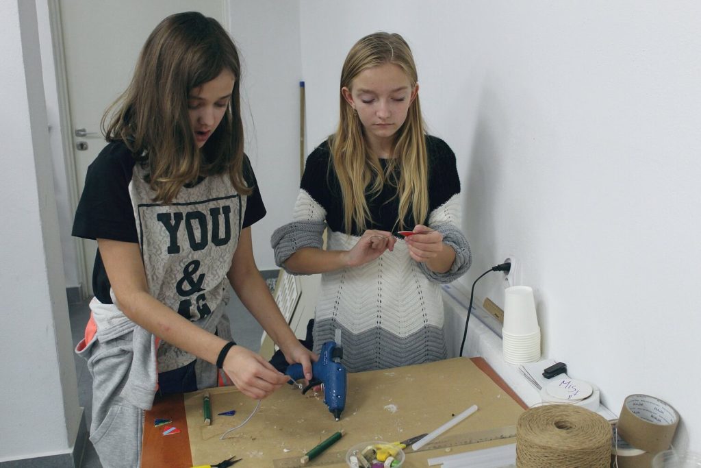 Dwie dziewczynki używają kleju na gorąco do stworzenia swoich prac