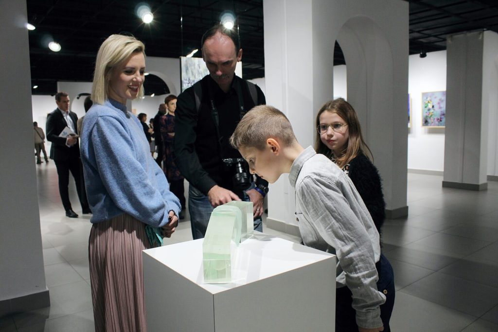Dzieci z rodzicami oglądający szklaną rzeźbę