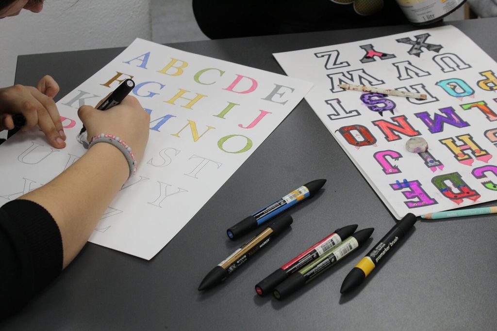 Dziewczynka koloruje litery alfabetu na kartce