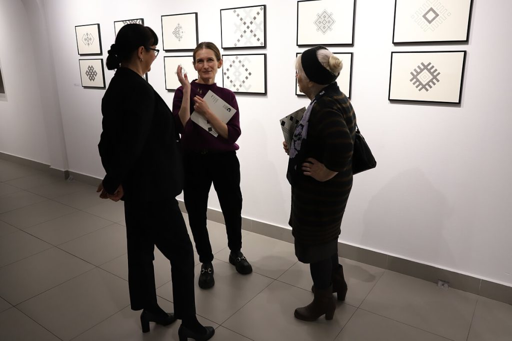 Laura Dyczko rozmawia z dwie kobietami zwiedzającymi wystawę