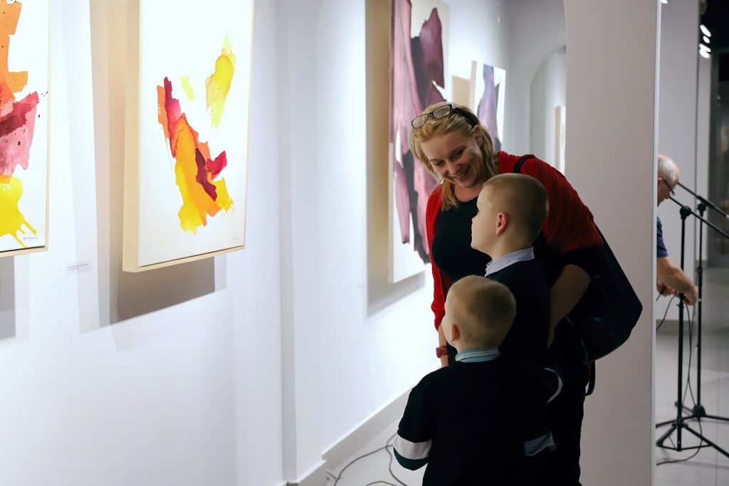 Mama z dziećmi zwiedzający wystawę obrazów Katarzyny Kręcickiej