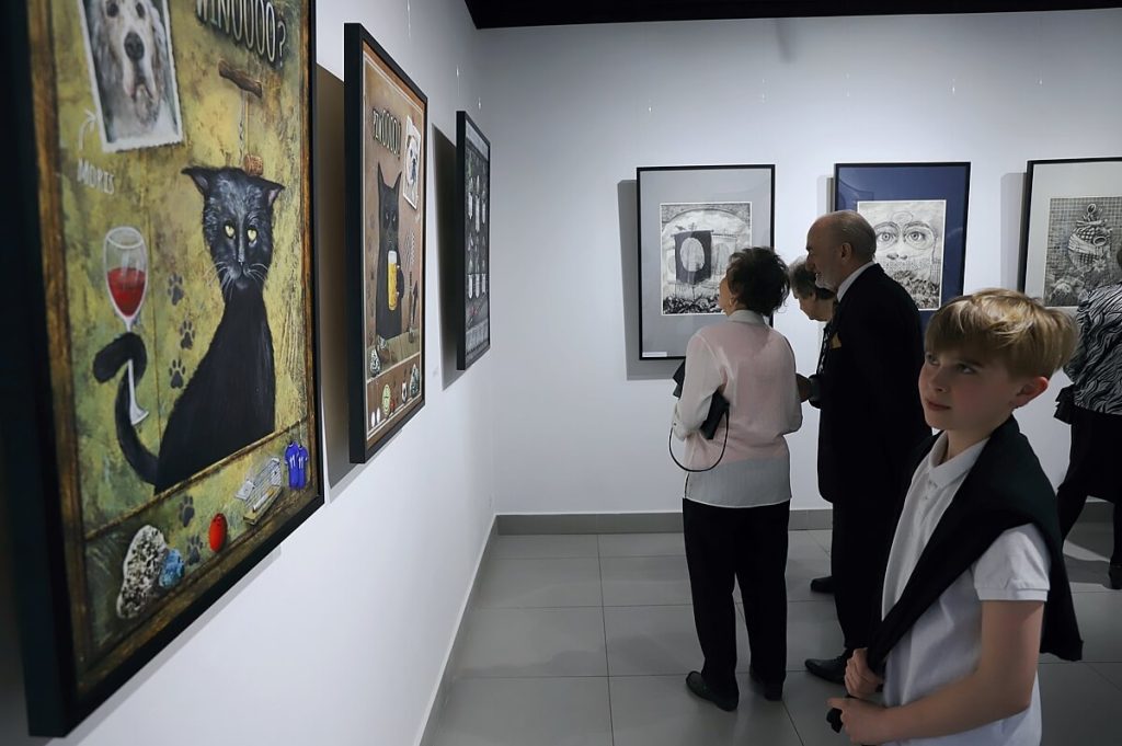 Chłopiec zwiedzający wystawę obrazów Wojciecha Akuszewskiego