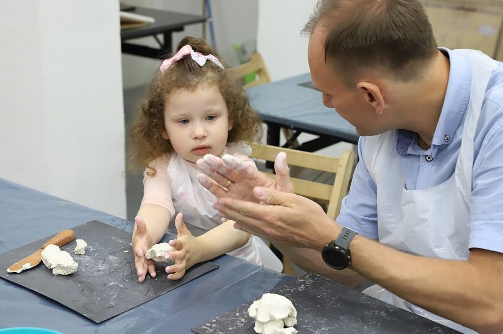 Dziewczynka z tatą tworzy figurki z gliny