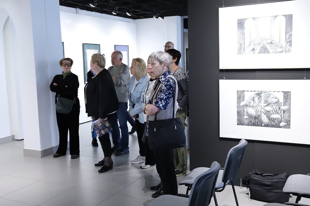 Uczestnicy oglądają obrazy i rysunki Wojciecha Akuszewskiego