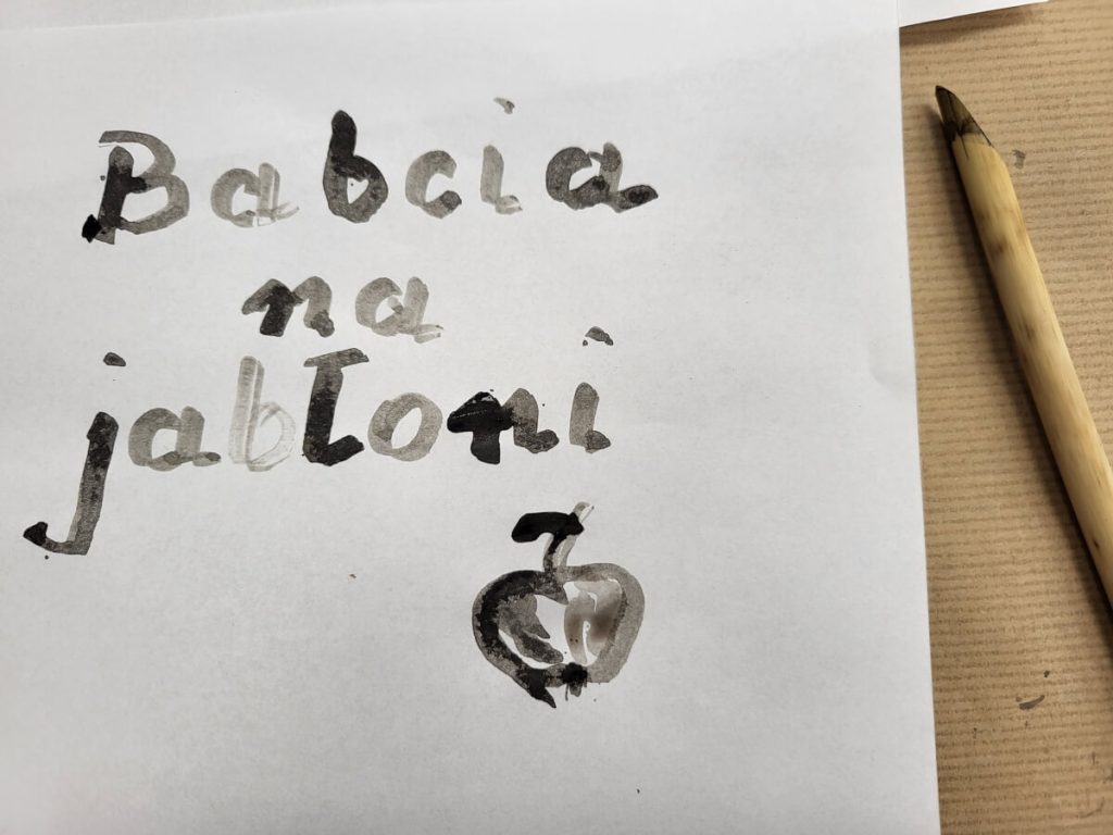 Napis Babcia na jabłoni wraz z rysunkiem jabłka wykonany tuszem do rysowania w trakcie warsztatu