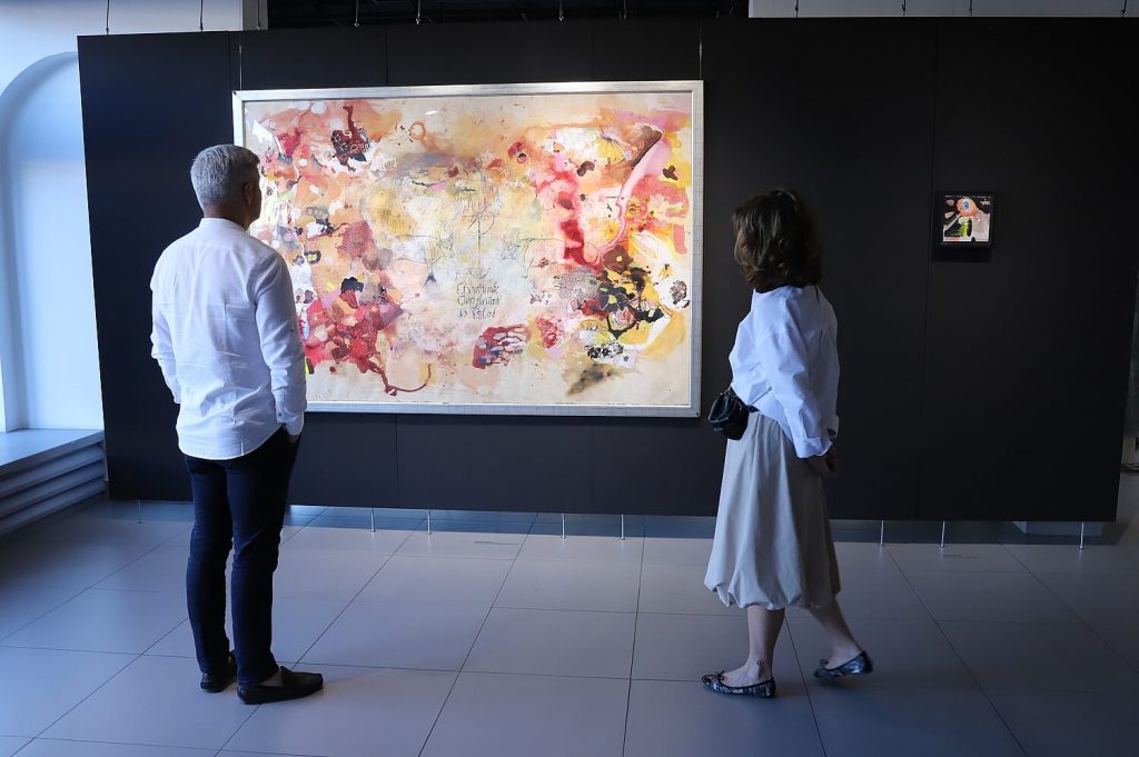 Mężczyzna i kobieta oglądają duży obraz Malwiny Bienias