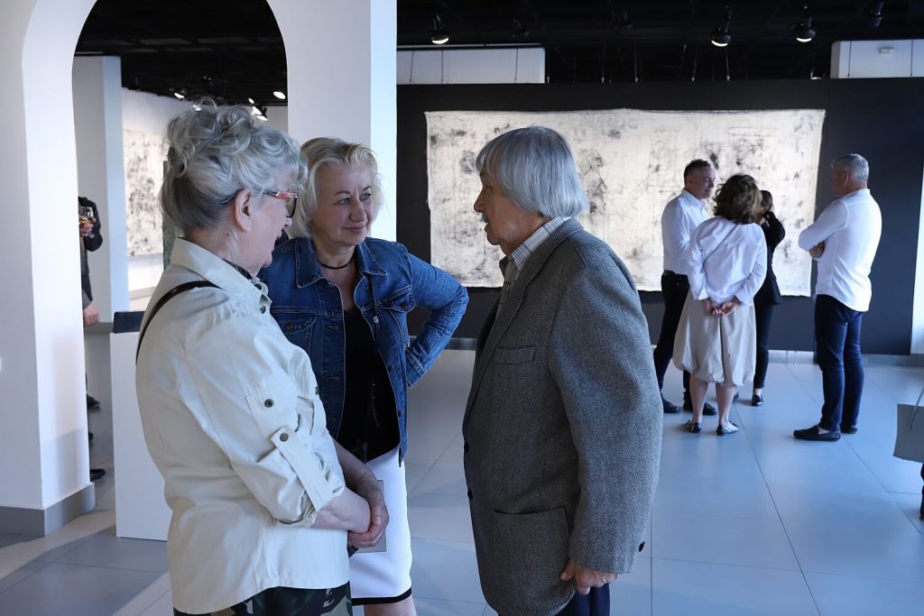 Goście wystawy dyskutujący na temat dzieł artysty