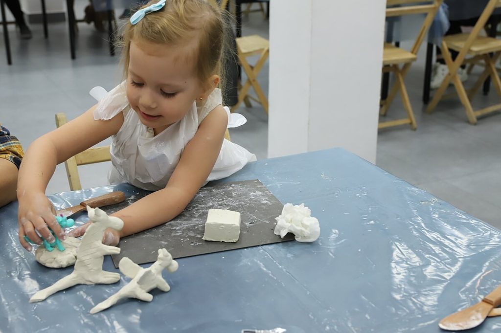 Dziewczynka tworzy figurki z gliny