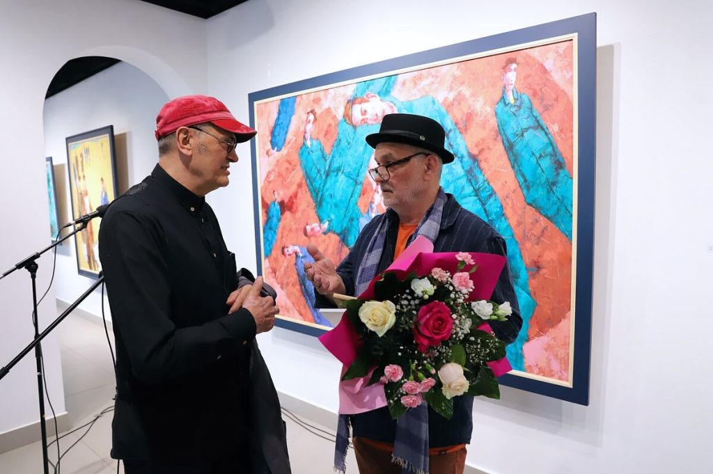 Waldemar J. Marszałek z kwiatami rozmawia podczas swojej wystawy