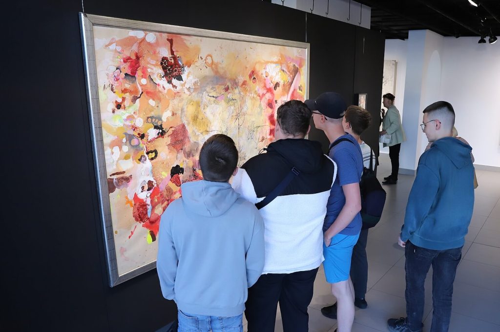 Grupa młodzieży ogląda obraz Malwiny Bienias