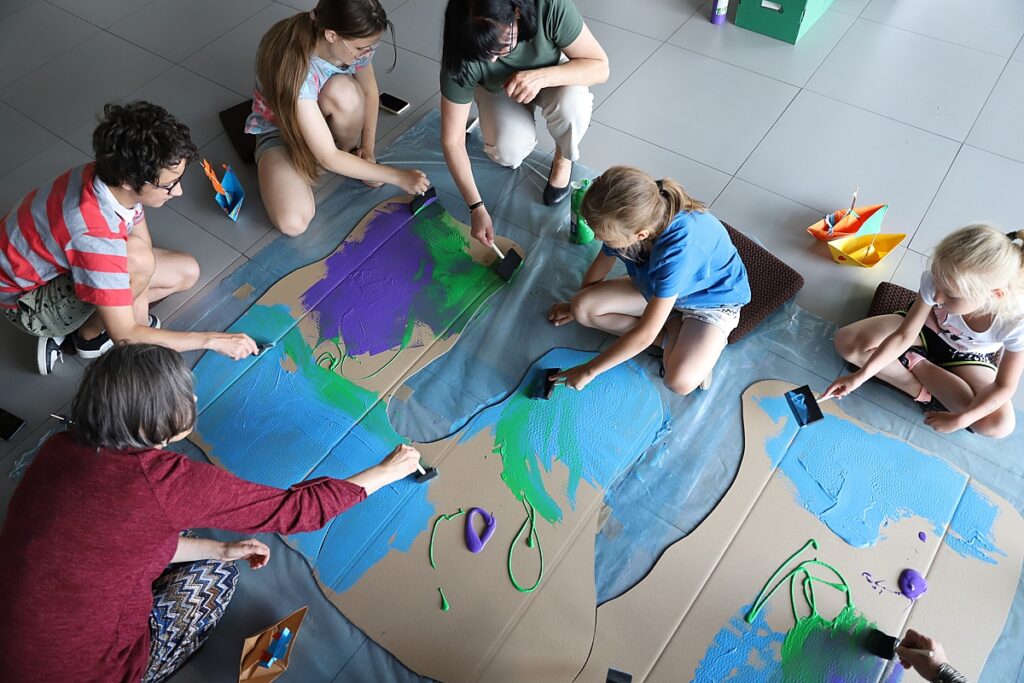 Grupka dzieci maluje farbami karton