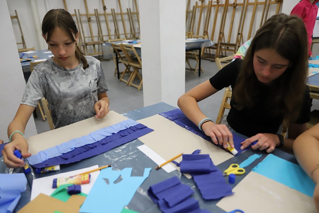 Dziewczynki wycinają z kolorowych papierów elementy swoich prac