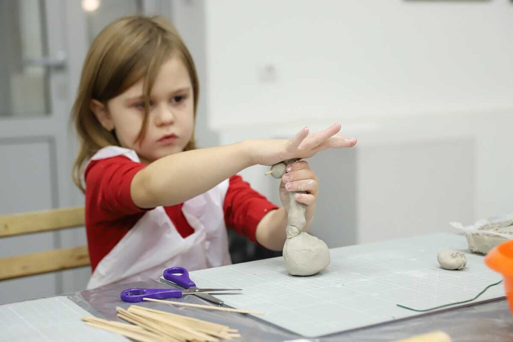 dziewczynka buduje figurkę z gliny