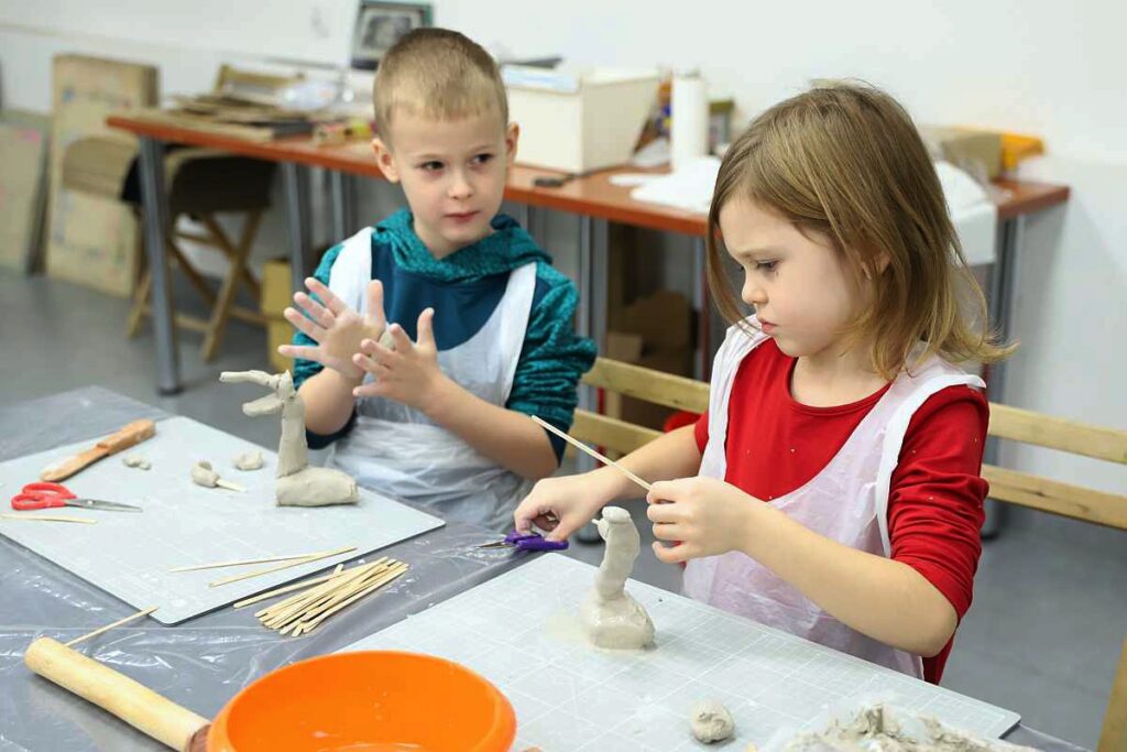 dziewczynka i chłopiec tworzą figurki dinozaurów