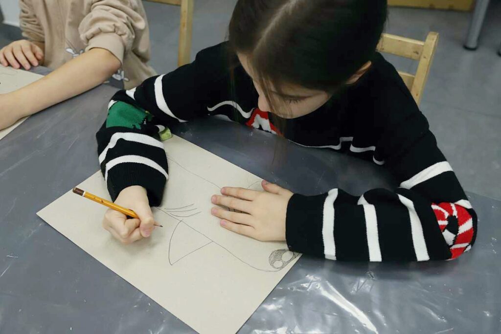 dziewczynka rysuje ołówkiem swój obrazek