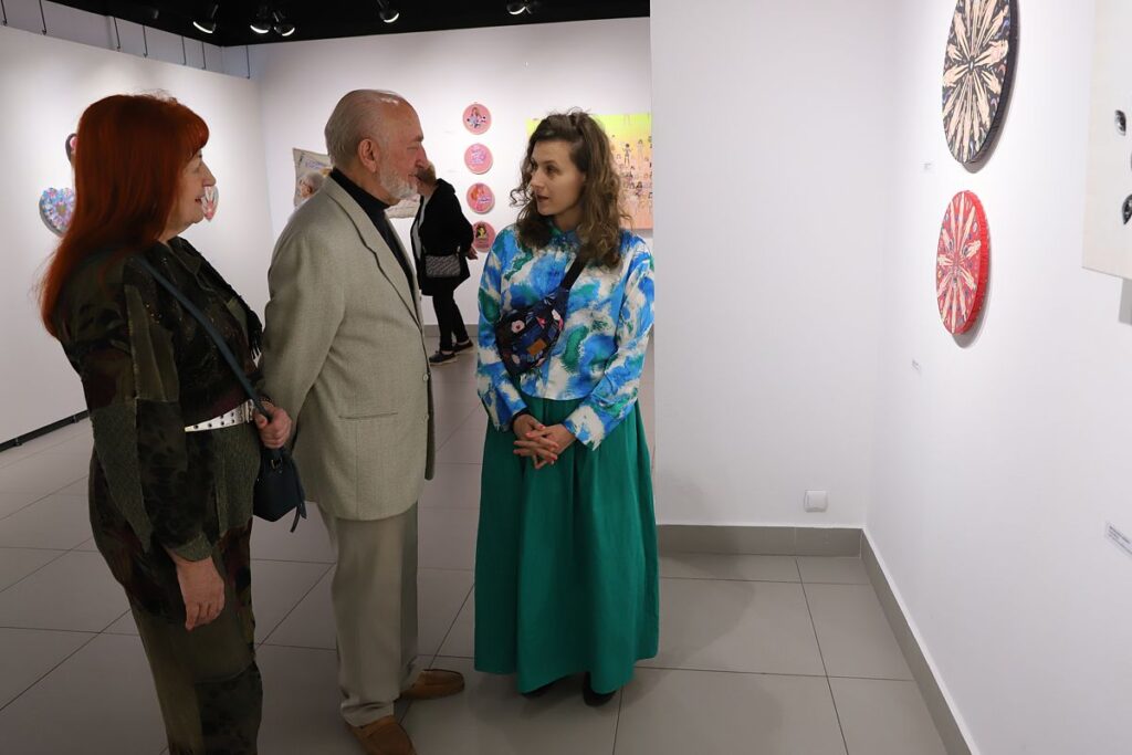 zwiedzający wraz z autorka w przestrzeni małej sali wystawowej